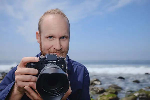 Brian Lipps holding a camera on the coast