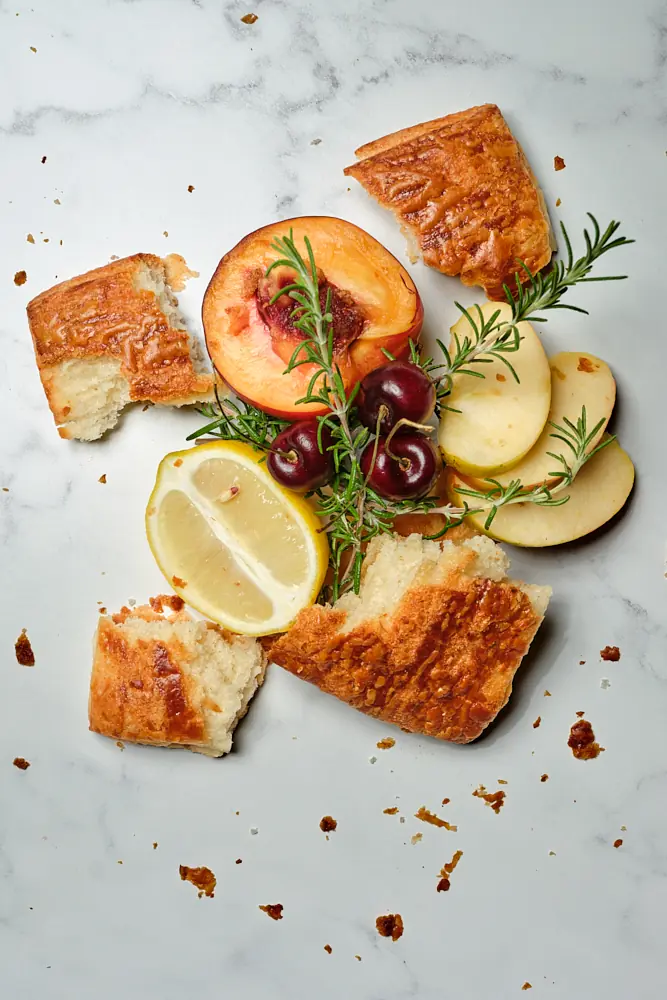 Golden pastry with sliced citrus, cherries, herbs, and scattered crumbs