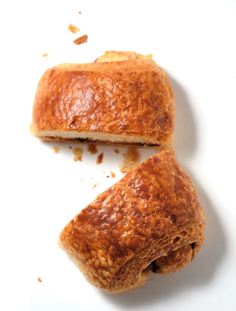 Golden pastry halves and crumbs arranged on white