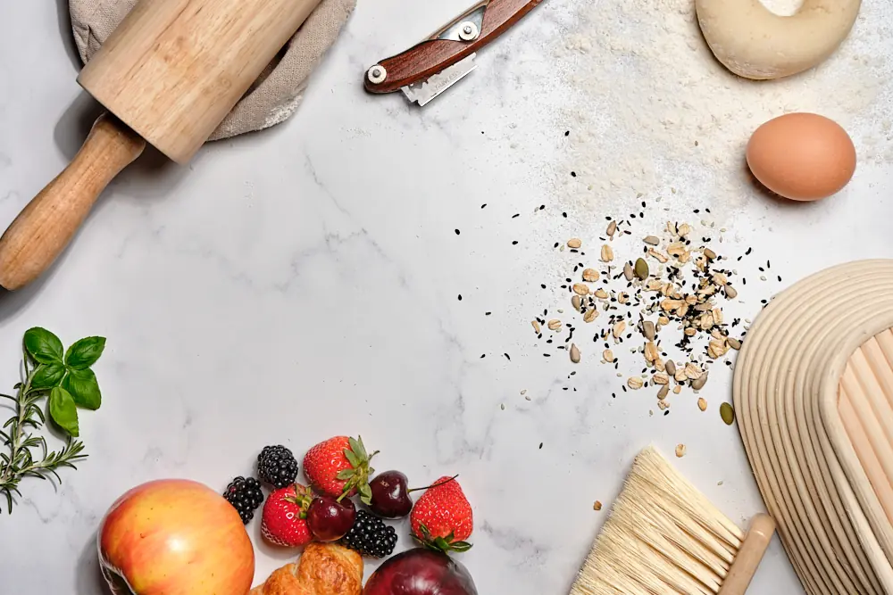 Overhead baking scene with rolling pin, ingredients, fruit, and herbs