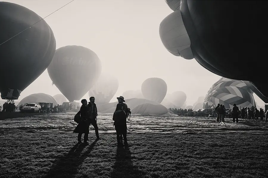 Silhouetted figures among hot-air balloons at dawn
