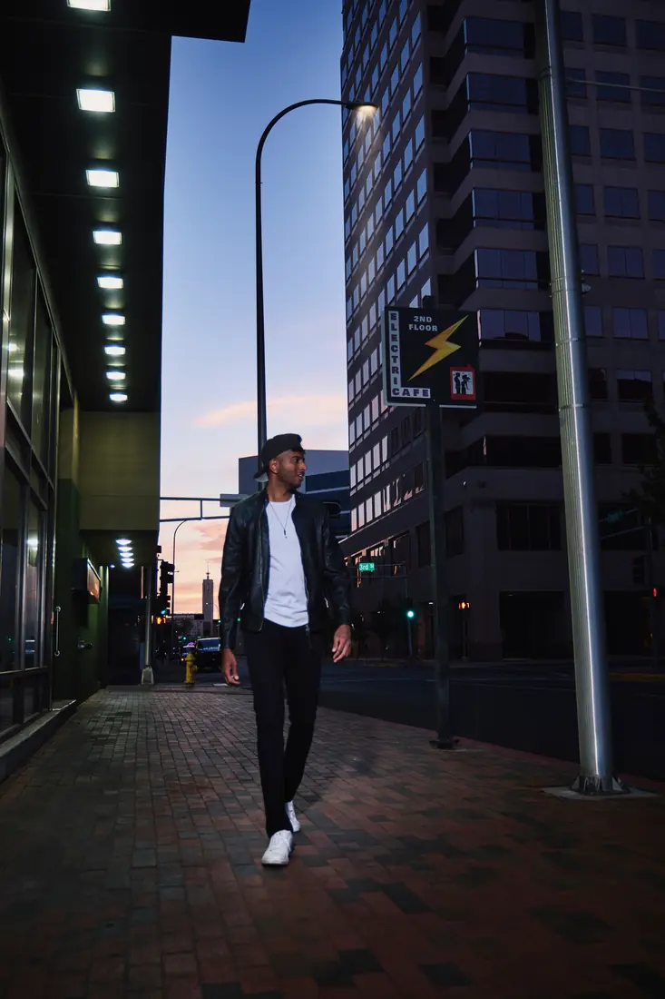 Man walking beneath city lights in a cinematic nighttime scene