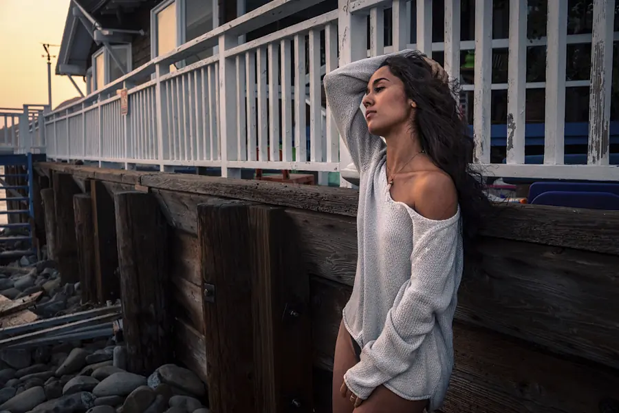 Woman in a gray sweater standing beside a weathered coastal pier