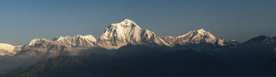 Wide view of the Himalayan range above shadowed foothills