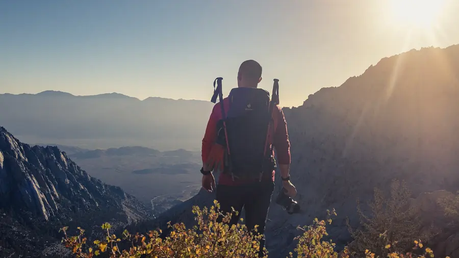 Backlit hiker crossing a high mountain ridge