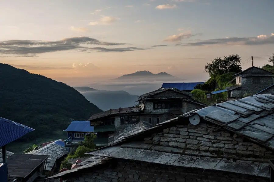 Dawn light settling over stone village rooftops and layered mountain valleys in Nepal