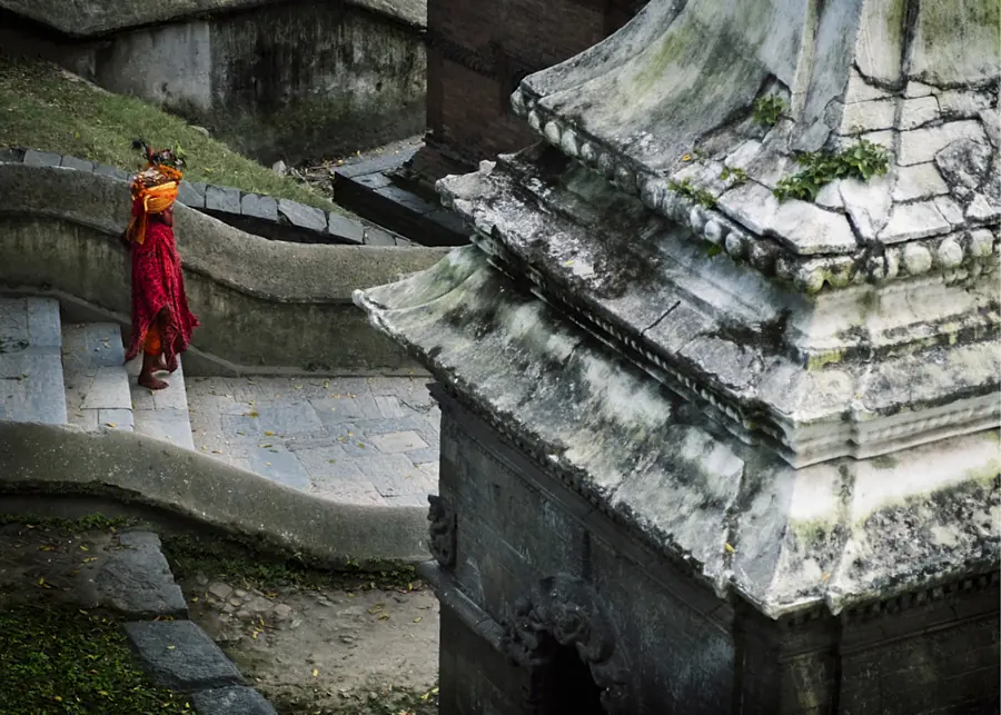 Monk in red walking through stone temple steps in Nepal