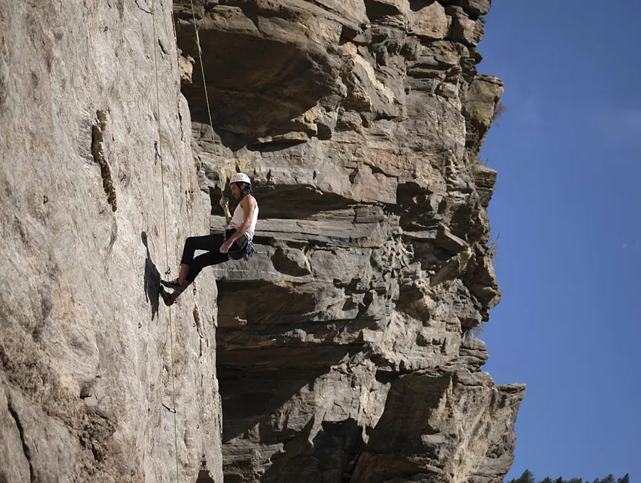 Rock climber moving across a steep golden cliff