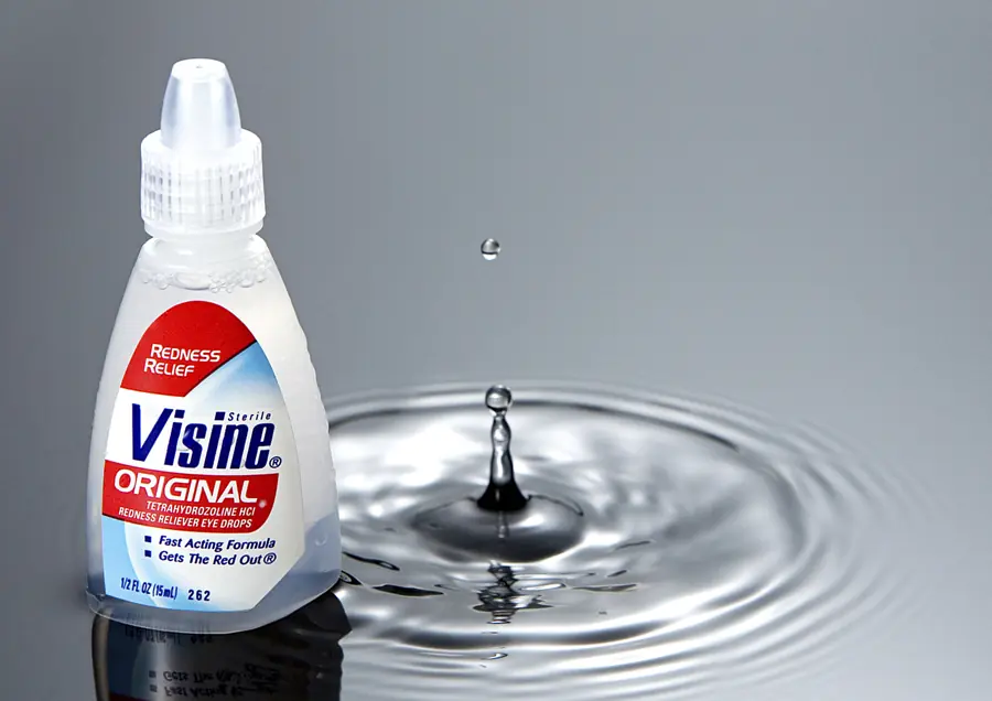 Visine bottle beside a suspended water drop and circular ripple